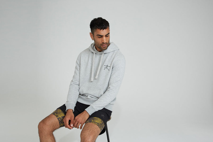 Mann in HEY HONEY grauem Hoodie mit Logo und gemusterten Shorts — klassischer Athleisure-Look