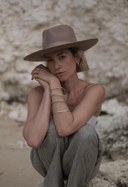 Hey Honey: Woman in a beige hat, striped pants, and silver bangles, looking at the camera.